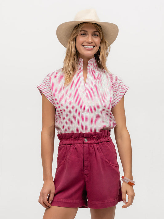 Smiling woman wearing a hat and a short sleeve shirt with pink polkadots